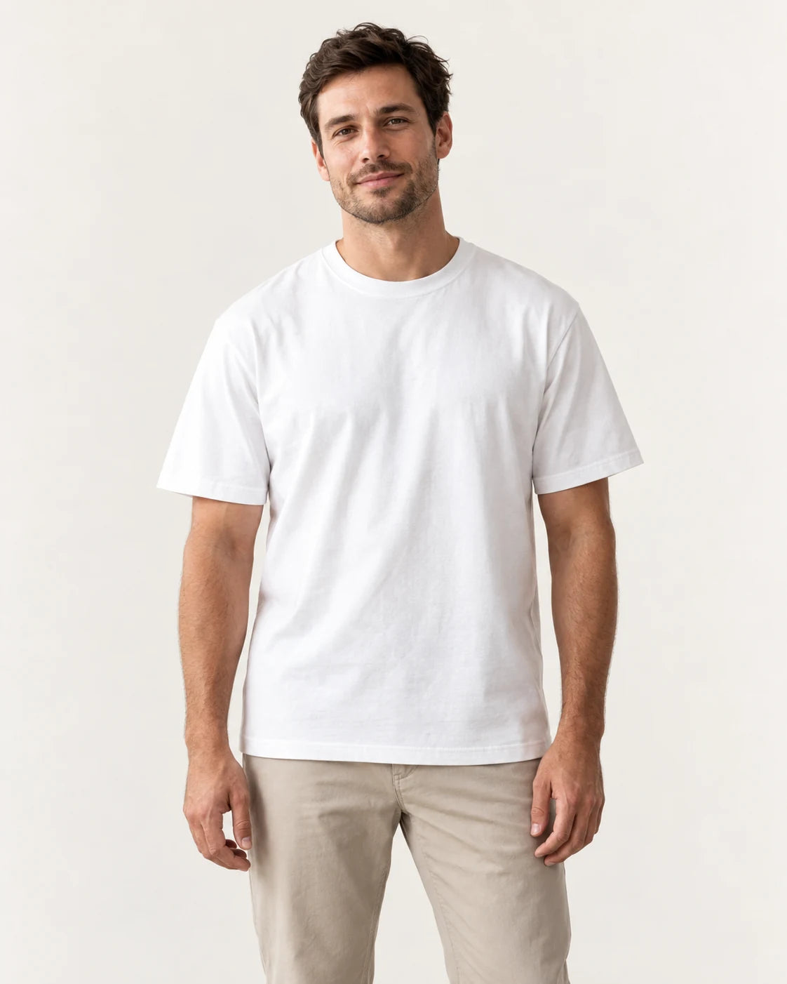 Man wearing a white crew-neck tee against a plain off-white studio background.